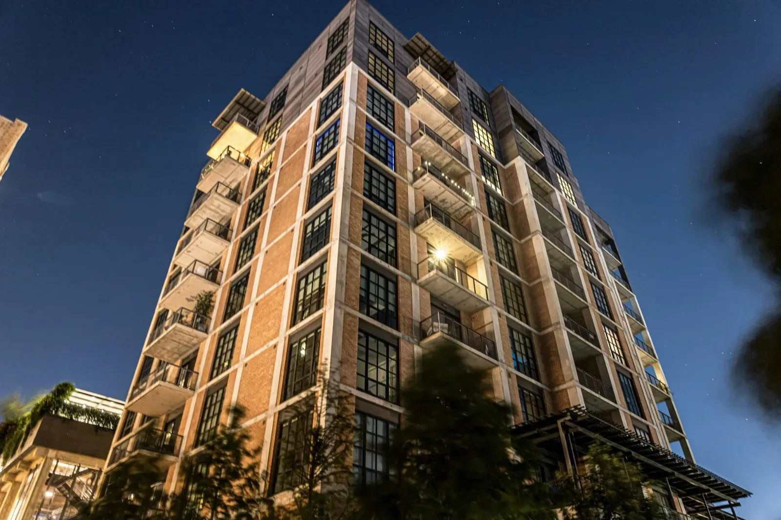 Tall brick and concrete building with balconies at night under a starry sky.