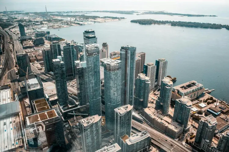 High aerial view of Toronto's downtown and waterfront with skyscrapers, highways, and the Toronto Islands.