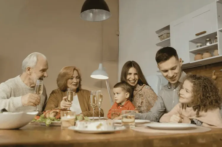 Multi-generational family smiling at a festive dinner table with food and drinks.