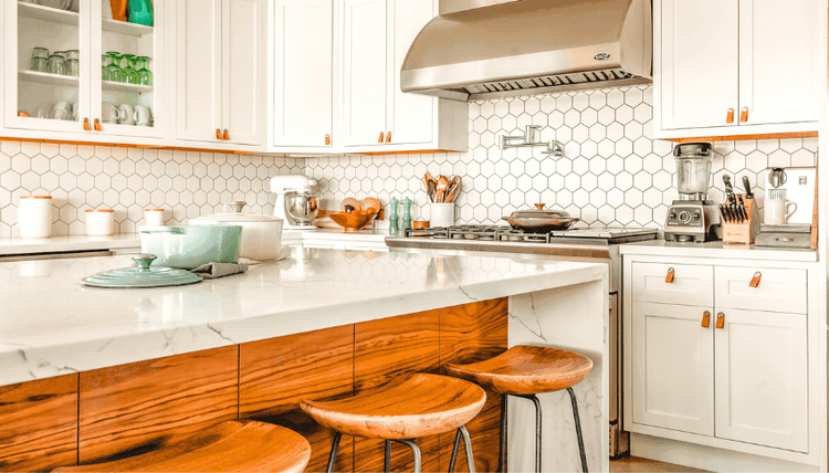 Modern kitchen with white cabinets, wood accents, hexagon tile backsplash, marble island, and bar stools.