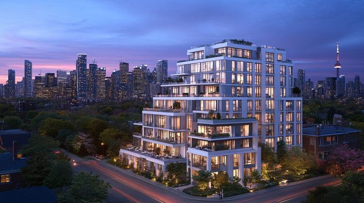 Luxury apartment building illuminated at dusk, street with car light trails, Toronto skyline & CN Tower in background.