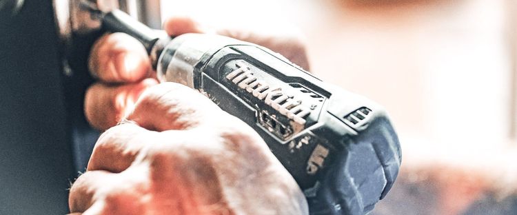 Close-up of hands holding a Makita impact driver