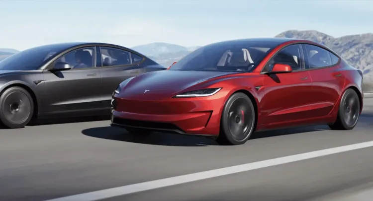 Sleek red Tesla Roadster and dark grey Tesla Model 3 driving on a highway, mountains in background.