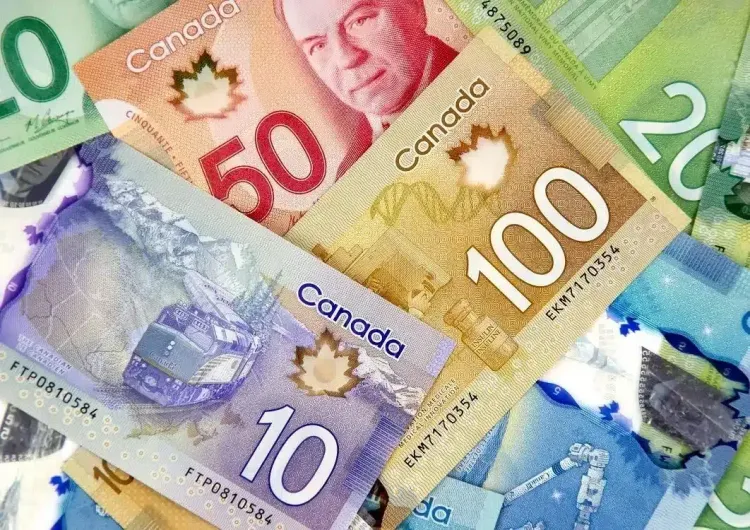 Close-up of various colorful Canadian dollar banknotes: $10, $20, $50, $100 bills overlapping.